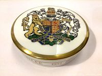 Top view of the round jewelry box lid showing the Royal Coat of Arms in full color with gold trim.
