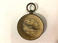 Top-down view of vintage brass compass with 'Germany' printed on dial, showing cardinal directions and degree markings.