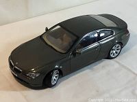 Front side angle view of Kyosho BMW 6 Series 1/18 model car in dark grey with detailed exterior and front grille visible.
