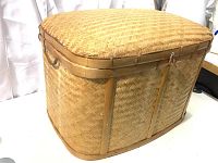 Front angled view of large woven picnic basket showing side handles and lock clasp