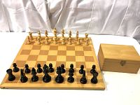 Wooden chess board set up with all chess pieces and storage box on the side.