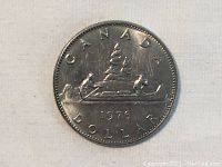 Obverse side of 1976 Canadian silver dollar coin showing two men paddling a canoe and date 1976.