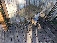 Front angled view of the gold metal MCM vinyl record holder and side table showing the top perforated surface and vinyl record storage rack with one vinyl record placed inside.