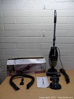 Small Chili II vacuum cleaner upright with original box, hose, crevice tool, round accessory, user manual, and power cord.