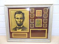 Full frontal view of framed display showing portrait, coins, stamps and blank nameplate area