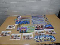 Photo showing all vintage Disneyland items, including Euro Disney bumper stickers, postcards, collector cards, and a map spread out on a table.