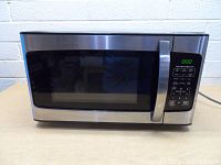 Front view of Hamilton Beach microwave oven showing stainless steel door, glass window, handle, and digital control panel with green LED display and buttons.