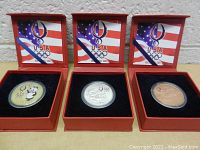 Front facing image showing three medallions in red display cases with American flag and USA Olympic logo inside lid.