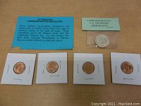 Four U.S. Treasury commemorative medallions in white cardboard holders arranged on a wooden surface with informational blue card included, showing obverse sides and packaging.