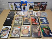 Photo of assorted DVD and Blu-ray cases arranged on a table showing multiple movie titles and TV series seasons.