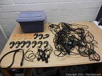 Gray plastic tub with lid on table along with cargo net, bungee cords and hooks neatly arranged.