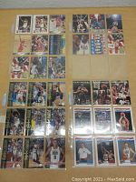 Photo of multiple USA Basketball cards featuring players including Michael Jordan, Magic Johnson, Karl Malone, and others arranged in a binder sleeve.