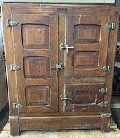 Front view of ice box showing double paneled doors, metal hardware, surface wear and scratches.