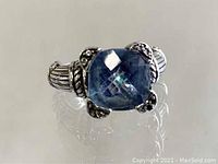 Front view of the sterling silver ring with cushion-cut blue-green stone highlighting the stone and silver detailing.