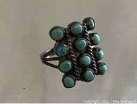 Front view showing eleven round turquoise stones set in a rectangular cluster with twisted silver rope borders, sterling silver band with triple split shank.