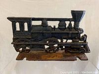 Front view of cast iron train engine door stop showing detailed chimney, whistle, and wheels on a flat base.