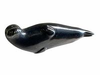 Profile view of the black stone carved seal or sea lion figurine showing smooth polished surface and head details.