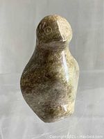 Front view of carved stone penguin showing polished smooth surface and basic facial features.
