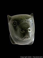 Front view of carved otter head sculpture showing detailed facial features and polished surface.