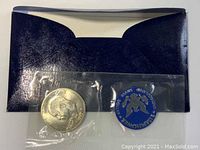 Close-up of the 1971 Eisenhower uncirculated silver dollar coin showing the detailed profile of Eisenhower and the informational medallion inside clear plastic sleeves in front of the black envelope.