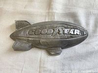 Top view of the Goodyear blimp aluminum paperweight on a neutral cloth background