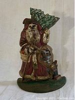 Front view of cast iron Santa Claus doorstop holding a tree and basket with detailed paint and texture.