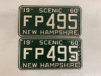 Front view of two 1960 New Hampshire scenic license plates numbered FP495, showing white embossing on green metal.