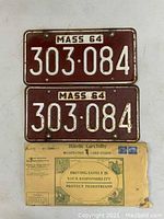Front side of the pair of maroon 1964 Massachusetts license plates numbered 303-084 with original envelope below.