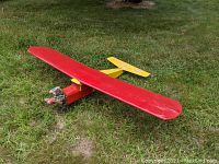 Side and front view of the red and yellow balsa wood RC airplane with OS Max engine installed, showing missing tail fin and wooden propeller