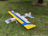 Front angle view of the Ultra Stick RC airplane showing yellow, white, and blue coloring and Enya engine at nose.