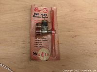 Photo of the vintage OK Cub .024 model airplane engine attached to original cardboard packaging showing product features and price.