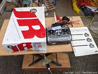 JR XP8103 8 channel radio controller, original box, manual, and charging cord displayed on wooden table.