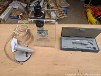 SCM Sandblasting High Speed Engraving unit with clear acrylic shield and hose nozzle attachment on a table next to a foam-padded case containing the engraving pen and accessory tips.