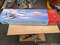 Box displaying ARC Galleggianti Floats kit with airplane images and branding on the top, resting on a wooden table.