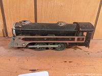 Side view of the Marx four-wheel locomotive toy showing black body with red and silver trim and metal wheels and rods