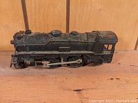 Side view of black Marx O scale 2-4-2 locomotive model, showing cab marked '999' and detailing on side rods and wheels.
