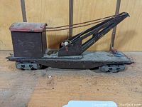 Side angled view of the tin wrecker car showing the crane arm extended with cables and the red roof cabin.