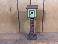 Front view of the Marx tin control tower toy showing the operator's box at the top with a lithographed operator figure inside and the red lattice tower base.