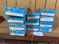 Photo showing eleven original blue Athearn HO Gauge train kits stacked in two piles on a wooden surface.