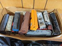Top-down view of box with multiple HO scale train cars assorted