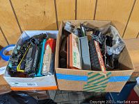 Wide view of lot showing a variety of HO gauge model train cars and engines in boxes, some loosely packed, showing wear and partial disassembly.
