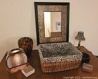 Photo showing entire set on wooden table including rectangular mirror, large wicker basket lined with leopard print fabric, two small leopard print lamps, tortoiseshell patterned vase, ashtray, and coasters.
