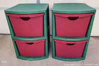 Two red and green stackable storage bins side by side, each with two drawers.