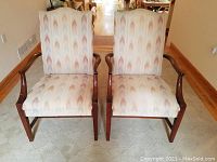 Front view of two vintage upholstered armchairs with wooden frames, showing seat and back upholstery with multi-color chevron patterned fabric.