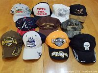 Photo of eleven various baseball caps arranged on wooden floor showing logos and color variety