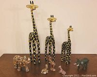 Photo showing three large giraffe figurines and several smaller animal figurines including tiger and elephant.