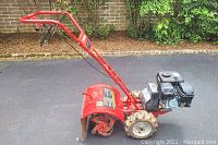 Side view showing overall machine, steel tines, wheels, engine and frame