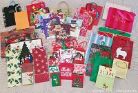 Overview of assorted Christmas and seasonal gift bags including various sizes and colors, showing holiday themes and one branded bag