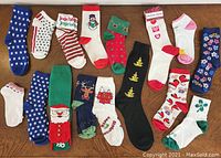 Sixteen pairs of women's holiday and fun themed socks laid flat.