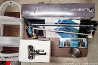 Overview of all bathroom fixtures and faucets on a wooden board, showing shower caddies, faucets, towel racks, toilet paper holder, and boxed showerhead combo.